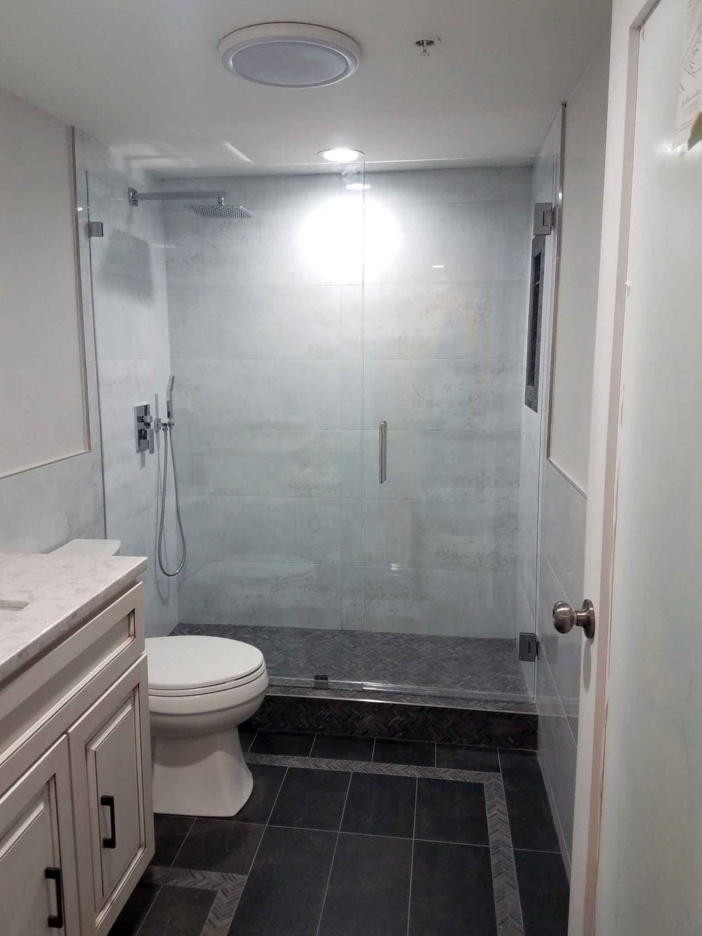 Bathroom remodel with frosted glass shower door and quartz vanity