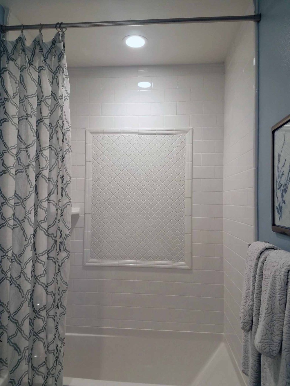 Frameless corner shower with wood-look tile and blue mosaic accent band